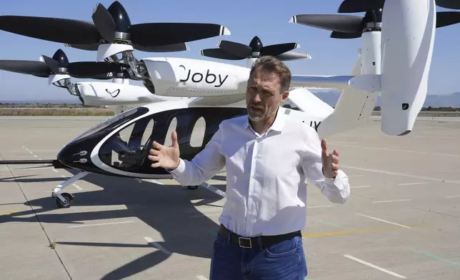 JoeBen Bevirt, CEO of Joby Aviation, stands next to an "electric vertical take-off and landing" aircraft, also known as an eVTOL, in Marina, Calif. on Monday, Oct. 7, 2024. (AP Photo/Terry Chea)