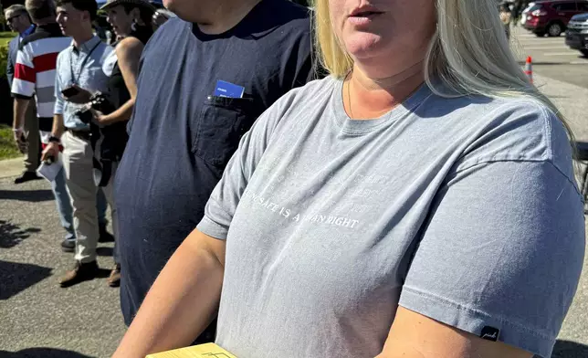 Shannon Doughty stands in front of her husband, Matt, while holding a wooden box on Aug. 29, 2024, in Westfield, Indiana, that had contained some of the cremated remains of her late brother Allen Livingston, who was identified in October 2023 as the ninth known victim of suspected serial killer Herbert Baumeister. (AP Photo/Rick Callahan)