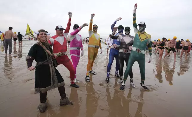 People dressed in costume pose in front of the North Sea after celebrating the arrival of the New Year during the traditional New Year's Dive in Ostende, Belgium, Saturday, Jan. 4, 2025. (AP Photo/Virginia Mayo)