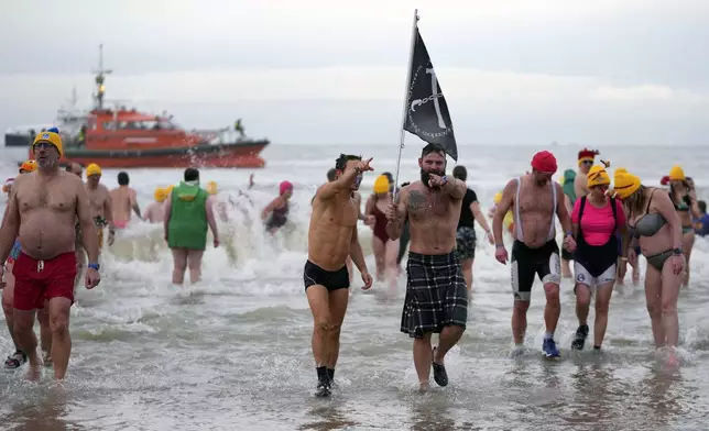 People dressed in costume walk out of the North Sea after celebrating the arrival of the New Year during the traditional New Year's Dive in Ostende, Belgium, Saturday, Jan. 4, 2025. (AP Photo/Virginia Mayo)