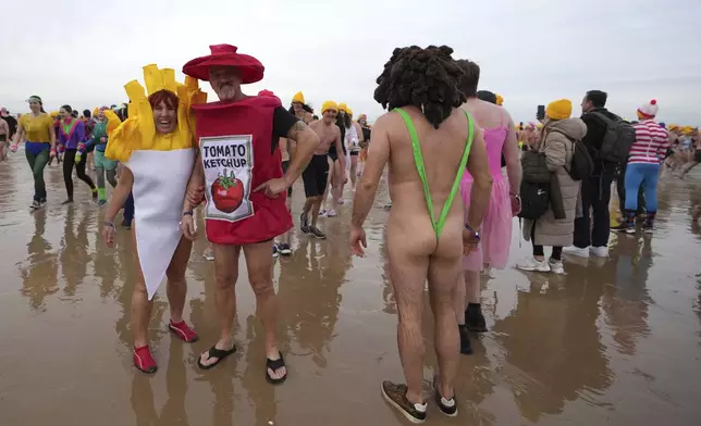 People dressed in costume pose in front of the North Sea after celebrating the arrival of the New Year during the traditional New Year's Dive in Ostende, Belgium, Saturday, Jan. 4, 2025. (AP Photo/Virginia Mayo)