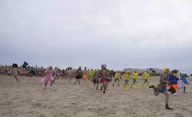 People, some dressed in costume, run toward the North Sea after celebrating the arrival of the New Year during the traditional New Year's Dive in Ostende, Belgium, Saturday, Jan. 4, 2025. (AP Photo/Virginia Mayo)