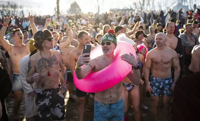 People warm up before taking a dip in the icy Tisza Lake near Tiszafured, Hungary, to celebrate the New Year on Saturday, Jan. 4, 2025. (AP Photo/Denes Erdos)