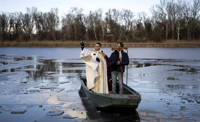 A priest blesses the Tisza Lake, before people take a dip in it to celebrate the New Year near Tiszafured, Hungary, on Saturday, Jan. 4, 2025. (AP Photo/Denes Erdos)