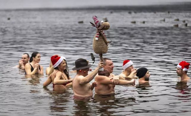 Swimmers get into the frigid waters to celebrate the arrival of the New Year during the traditional New Year's Dive in a lake near Vilnius, Lithuania, Wednesday, Jan. 1, 2025. (AP Photo/Mindaugas Kulbis)