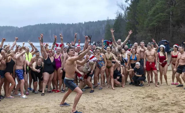 Swimmers pose for a photo after swimming during the traditional New Year's Dive in a lake near Vilnius, Lithuania, Wednesday, Jan. 1, 2025. (AP Photo/Mindaugas Kulbis)