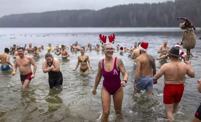 Swimmers enter the water during the traditional New Year's Dive in a lake near Vilnius, Lithuania, Wednesday, Jan. 1, 2025. (AP Photo/Mindaugas Kulbis)