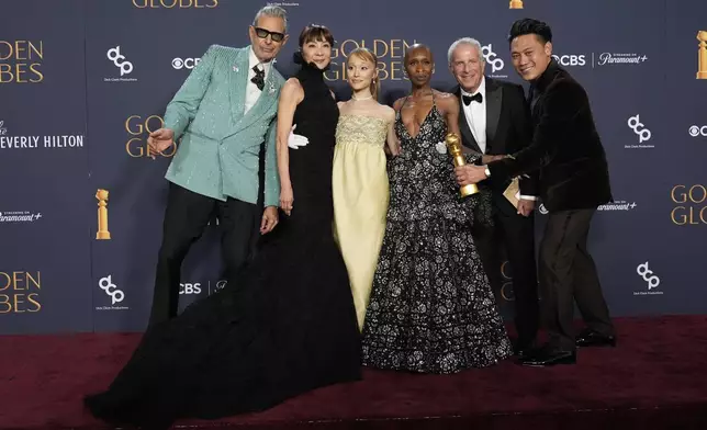 Jeff Goldblum, from left, Michelle Yeoh, Ariana Grande, Cynthia Erivo, Marc Platt, and Jon M. Chu pose with the award for cinematic and box office achievement for "Wicked" in the press room during the 82nd Golden Globes on Sunday, Jan. 5, 2025, at the Beverly Hilton in Beverly Hills, Calif. (AP Photo/Chris Pizzello)