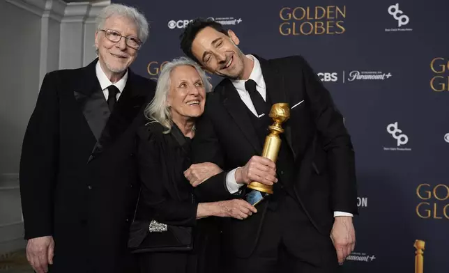 Elliot Brody, from left, Sylvia Plachy, and Adrien Brody, winner of the award for best performance by a male actor in a motion picture drama for "The Brutalist", pose in the press room during the 82nd Golden Globes on Sunday, Jan. 5, 2025, at the Beverly Hilton in Beverly Hills, Calif. (AP Photo/Chris Pizzello)