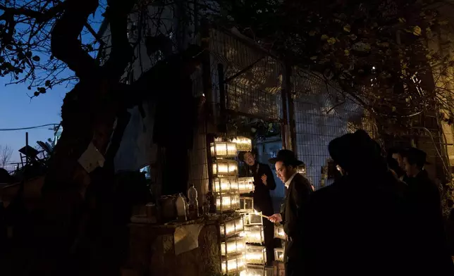 Ultra-Orthodox Jewish yeshiva students light candles to mark the holiday of Hanukkah in Jerusalem, Wednesday, Jan. 1, 2025. (AP Photo/Maya Alleruzzo)