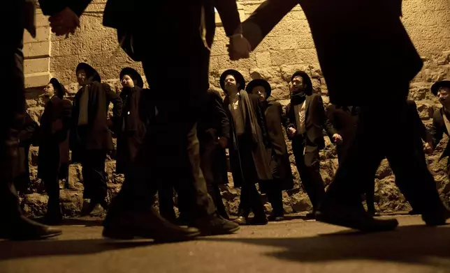 Ultra-Orthodox Jewish yeshiva students dance after lighting candles to mark the holiday of Hanukkah in Jerusalem, Wednesday, Jan. 1, 2025. (AP Photo/Maya Alleruzzo)