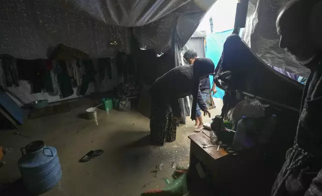 Manal Lubbad, a 49-year-old mother of eight and a displaced woman from Gaza City, tries to clean her flooded tent after heavy overnight rainfall at the refugee tent camp for displaced Palestinians in Deir al-Balah, central Gaza Strip, Tuesday, Dec. 31, 2024. (AP Photo/Abdel Kareem Hana)