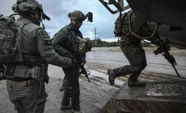 Israeli soldiers board an armored vehicle to enter the Gaza Strip at the Israel-Gaza border in southern Israel on Tuesday, Dec. 31, 2024. (AP Photo/Tsafrir Abayov)