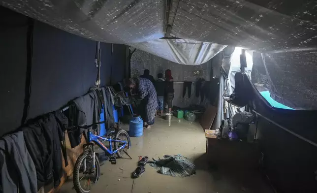 Nabil Lubbad tries to clean his family's flooded tent after heavy overnight rainfall at the refugee tent camp for displaced Palestinians in Deir al-Balah, central Gaza Strip, Tuesday, Dec. 31, 2024. (AP Photo/Abdel Kareem Hana)