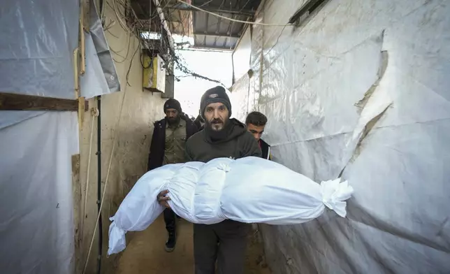 The body of a victim of an Israeli army strike on a house in the Bureij refugee camp is carried for the funeral at the Al-Aqsa Martyrs Hospital in the central Gaza Strip town of Deir al-Balah Wednesday, Jan. 1, 2025. (AP Photo/Abdel Kareem Hana)