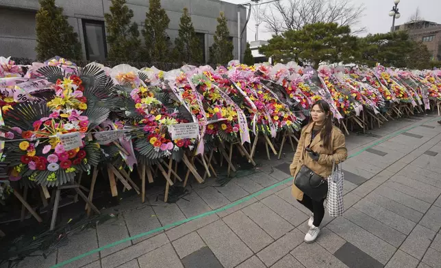 A pedestrian passes by the wreaths sent by supporters of impeached South Korean President Yoon Suk Yeol outside of the Constitutional Court in Seoul, South Korea, Tuesday, Jan. 14, 2025. (AP Photo/Lee Jin-man)