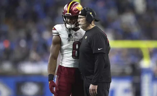 Washington Commanders running back Brian Robinson Jr. (8) talks with Washington head coach Dan Quinn during the second half of an NFL football divisional playoff game against the Detroit Lions, Saturday, Jan. 18, 2025, in Detroit. (AP Photo/Mike Mulholland)