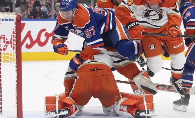 Edmonton Oilers' Connor McDavid (97) crashes into Anaheim Ducks' goalie Lukas Dostal (1) during second-period NHL hockey game action in Edmonton, Alberta, Friday, Jan. 3, 2025. (Jason Franson/The Canadian Press via AP)