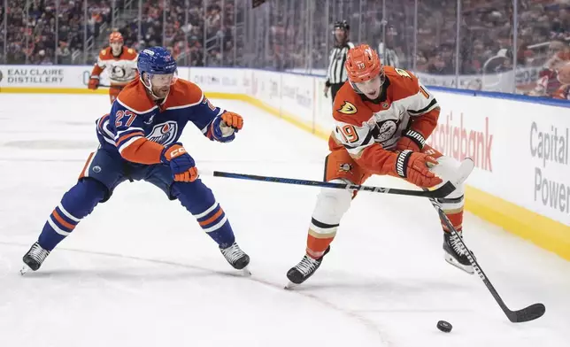 Anaheim Ducks' Troy Terry (19) and Edmonton Oilers' Brett Kulak (27) battle for the puck during third-period NHL hockey game action in Edmonton, Alberta, Friday, Jan. 3, 2025. (Jason Franson/The Canadian Press via AP)