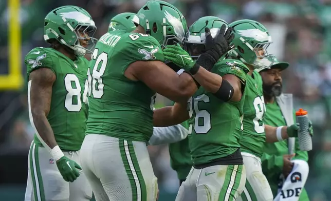 Philadelphia Eagles running back Saquon Barkley, right, is congratulated by offensive tackle Jordan Mailata after Barkley rushed for a long run to put him over 2,000 yards for the season during the second half of an NFL football game, Sunday, Dec. 29, 2024, in Philadelphia. (AP Photo/Matt Slocum)