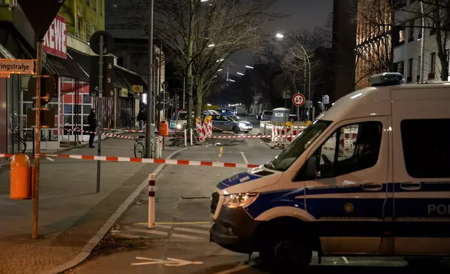 Police officers stand guard in front of a Rewe Market after a knife attack, in Berlin, Germany, Tuesday, Dec. 31, 2024. (AP Photo/Ebrahim Noroozi)