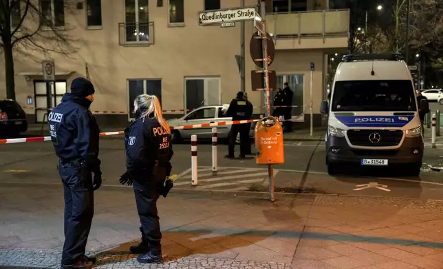 Police officers stand guard in front of a Rewe Market after a knife attack, in Berlin, Germany, Tuesday, Dec. 31, 2024. (AP Photo/Ebrahim Noroozi)