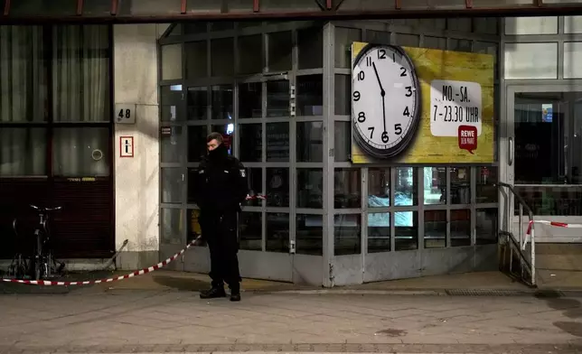 A Police officer stands guard in front of a Rewe Market after a knife attack, in Berlin, Germany, Tuesday, Dec. 31, 2024. (AP Photo/Ebrahim Noroozi)