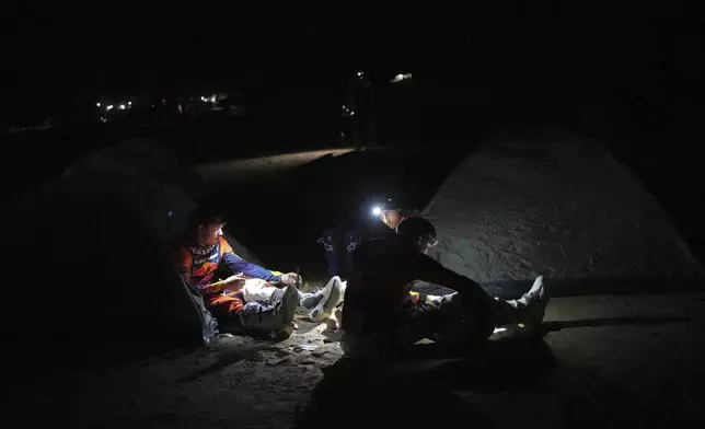 Riders have dinner at the bivouac area after stage two of the Dakar Rally with start in Bisha and finish in Bisha, Saudi Arabia, Sunday, Jan. 5, 2025. (AP Photo/Christophe Ena)