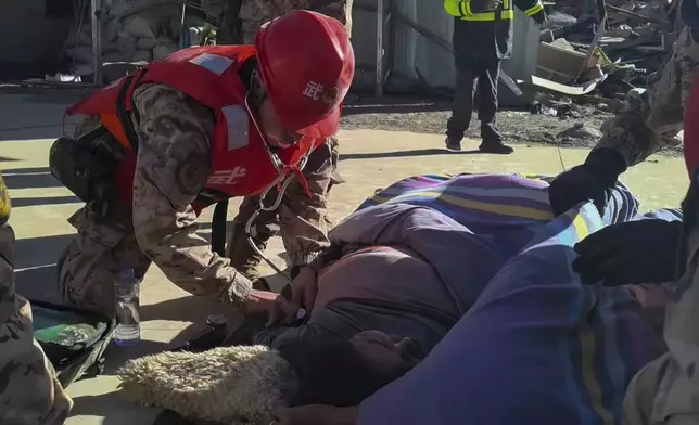 In this photo released by Xinhua News Agency, rescue workers check on an injured resident in the aftermath of an earthquake in Changsuo Township of Dingri in Xigaze, southwestern China's Tibet Autonomous Region on Tuesday, Jan. 7, 2025. (Liu Yousheng/Xinhua via AP)