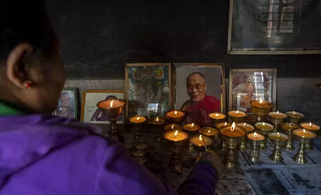 A Tibetan woman lights a butter lamp and offers a prayer in the remembrance of those who lost their lives in the recent earthquake, at a Tibetan camp in Lalitpur, Nepal, on Wednesday, Jan. 8, 2025. (AP Photo/Niranjan Shrestha)