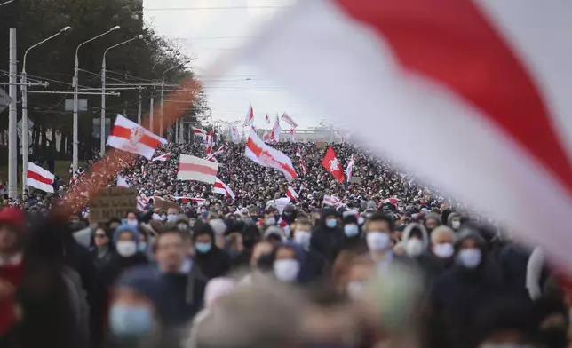 FILE - People carrying an old Belarusian national flag ,that has become an anti-government symbol, march in an opposition rally to protest the presidential election results in Minsk, Belarus, on Oct. 18, 2020. (AP Photo, File)
