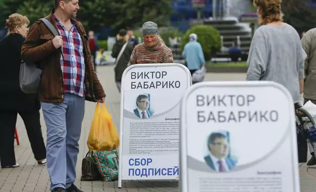 FILE - People walk past informational posters supporting Viktar Babaryka, who wanted to run in the upcoming presidential elections, in Minsk, Belarus, on June 14, 2020. (AP Photo/Sergei Grits, File)