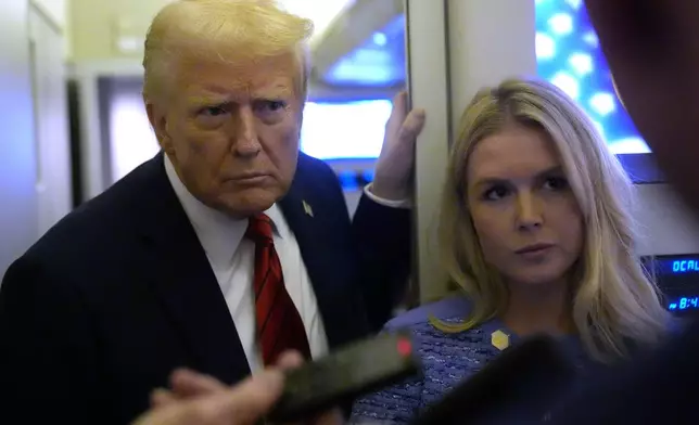 President Donald Trump speaks to reporters aboard Air Force One en route from Miami to Joint Base Andrews, Md., Monday, Jan. 27, 2025, as White House press secretary Karoline Leavitt listens. (AP Photo/Mark Schiefelbein)