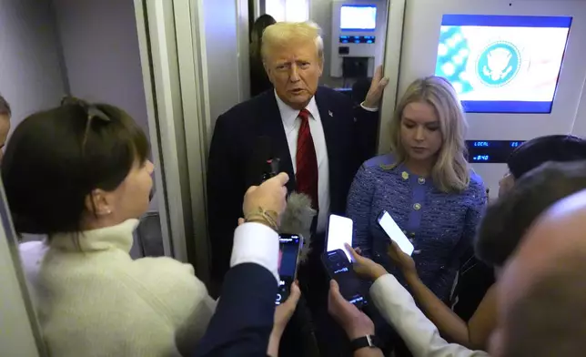 President Donald Trump speaks to reporters aboard Air Force One en route from Miami to Joint Base Andrews, Md., Monday, Jan. 27, 2025, as White House press secretary Karoline Leavitt listens. (AP Photo/Mark Schiefelbein)