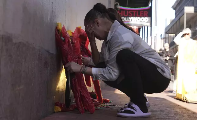 Samantha Petry places flowera at a memorial on Canal and Bourbon Street, Thursday, Jan. 2, 2025 in New Orleans. (AP Photo/George Walker IV)