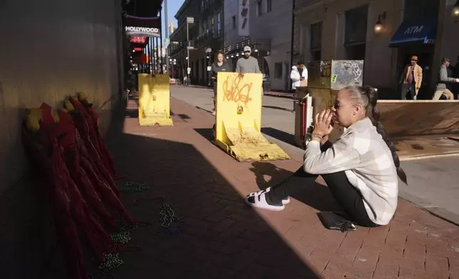 Samantha Petry, who works in the area, visits a flower memorial set up on Canal and Bourbon Street, Thursday, Jan. 2, 2025 in New Orleans. (AP Photo/George Walker IV)