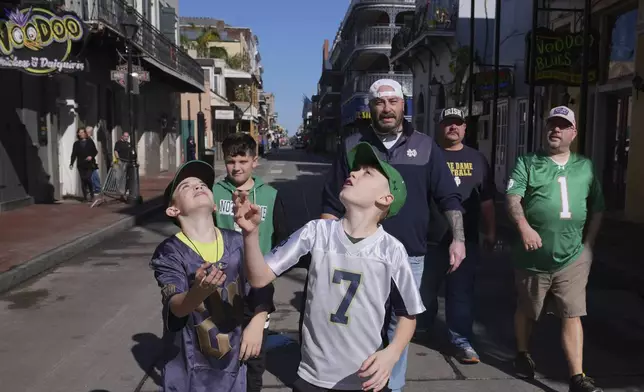 Cory Hunter throws a coin in the air on Bourbon Street, Thursday, Jan. 2, 2025 in New Orleans. (AP Photo/George Walker IV)