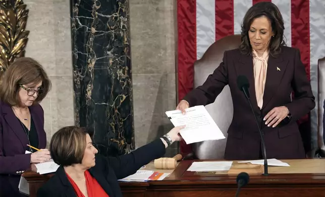 Vice President Kamala Harris hands the certification for Virginia to teller Sen. Amy Klobuchar, D-Minn., during joint session of Congress to confirm the Electoral College votes, affirming President-elect Donald Trump's victory in the presidential election, Monday, Jan. 6, 2025, at the U.S. Capitol in Washington. (AP Photo/Matt Rourke)