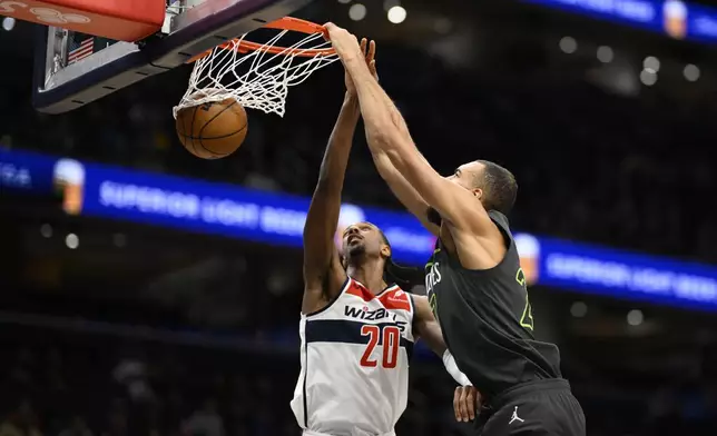 Minnesota Timberwolves center Rudy Gobert, right, dunks over Washington Wizards forward Alex Sarr (20) during the first half of an NBA basketball game, Monday, Jan. 13, 2025, in Washington. (AP Photo/Nick Wass)