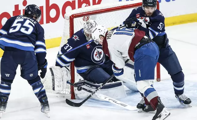 Winnipeg Jets goaltender Connor Hellebuyck (37) saves the shot as Dylan Coghlan (52) defends against Colorado Avalanche's Juuso Parssinen (16) during second period NHL action in Winnipeg on Saturday, January 11, 2025. (John Woods/The Canadian Press via AP)