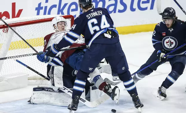 Winnipeg Jets goaltender Connor Hellebuyck (37) saves the shot as Logan Stanley (64) defends against Colorado Avalanche's Parker Kelly (17) during second period NHL action in Winnipeg on Saturday, January 11, 2025. (John Woods/The Canadian Press via AP)