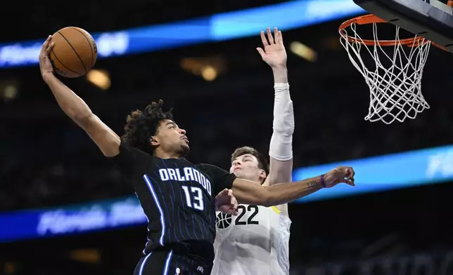 Orlando Magic guard Jett Howard (13) goes up to dunk as Utah Jazz forward Kyle Filipowski (22) defends during the second half of an NBA basketball game, Sunday, Jan. 5, 2025, in Orlando, Fla. (AP Photo/Phelan M. Ebenhack)