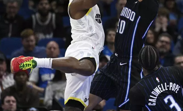 Utah Jazz guard Collin Sexton, left, goes up to shoot as Orlando Magic guard Cole Anthony, top right, defends during the first half of an NBA basketball game, Sunday, Jan. 5, 2025, in Orlando, Fla. (AP Photo/Phelan M. Ebenhack)