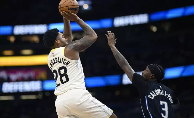 Utah Jazz forward Brice Sensabaugh (28) shoots in front of Orlando Magic guard Kentavious Caldwell-Pope (3) during the first half of an NBA basketball game, Sunday, Jan. 5, 2025, in Orlando, Fla. (AP Photo/Phelan M. Ebenhack)