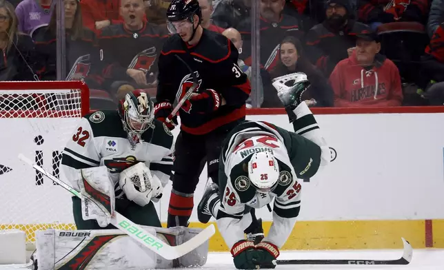 Carolina Hurricanes' Andrei Svechnikov (37) chases the puck between Minnesota Wild's Jonas Brodin (25) and goaltender Filip Gustavsson (32) during the first period of an NHL hockey game in Raleigh, N.C., Saturday, Jan. 4, 2025. (AP Photo/Karl DeBlaker)