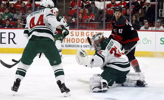 Minnesota Wild goaltender Filip Gustavsson (32) catches the puck between teammate Travis Dermott (44) and Carolina Hurricanes' Jesperi Kotkaniemi (82) during the second period of an NHL hockey game in Raleigh, N.C., Saturday, Jan. 4, 2025. (AP Photo/Karl DeBlaker)