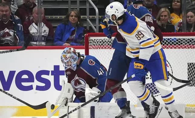 Colorado Avalanche goaltender Scott Wedgewood, back, makes a stick save on a shot as defenseman Josh Manson, center, jostles for position with Buffalo Sabres right wing Alex Tuch in front of the net in the first period of an NHL hockey game Thursday, Jan. 2, 2025, in Denver. (AP Photo/David Zalubowski)