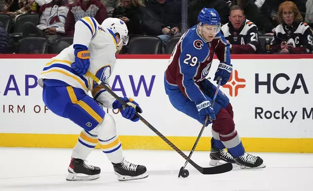 Colorado Avalanche center Nathan MacKinnon, right, drives with the puck as Buffalo Sabres defenseman Bowen Byram covers in the first period of an NHL hockey game Thursday, Jan. 2, 2025, in Denver. (AP Photo/David Zalubowski)