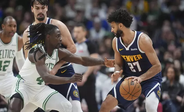 Denver Nuggets guard Jamal Murray, right, looks to pass the ball as Boston Celtics guard Jrue Holiday defends in the first half of an NBA basketball game, Tuesday, Jan. 7, 2025, in Denver. (AP Photo/David Zalubowski)