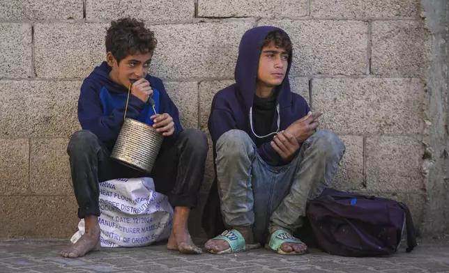 Two Palestinian boys wait to collect donated food at a food distribution center in Deir al-Balah, central Gaza Strip, Thursday Jan. 2, 2025. (AP Photo/Abdel Kareem Hana)